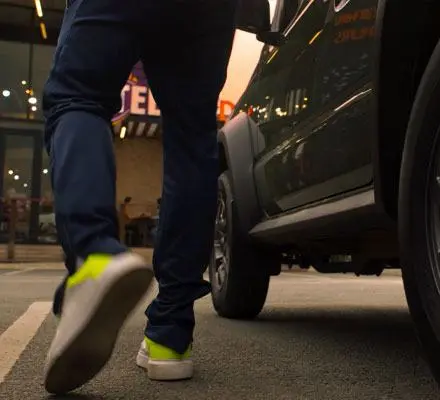 A man walking pass a vehicle in the direction of a Steers restaurant