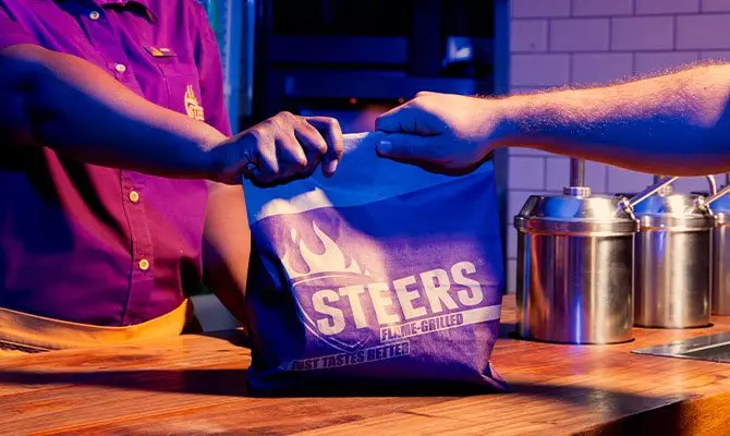 Cashier handing off a takeaway parcel to a customer