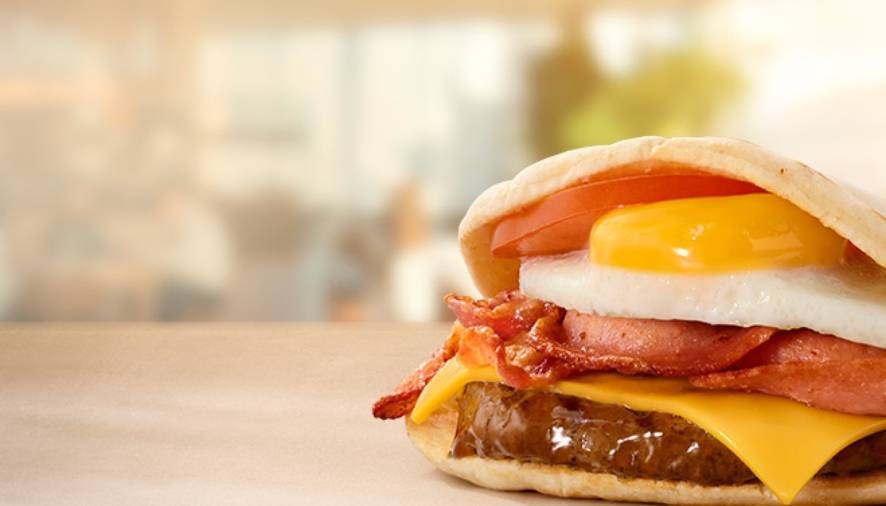 Breakfast pita filled with fried egg, bacon, beef patty, cheese and tomato