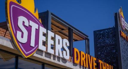 Steers Drive Thru signage with the Steers flame logo against a blue sky