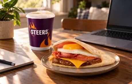 Breakfast pita and coffee on a desk next to a laptop for a work-from-home breakfast