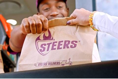 Smiling customer receiving a Steers takeaway breakfast bag at the drive-thru window