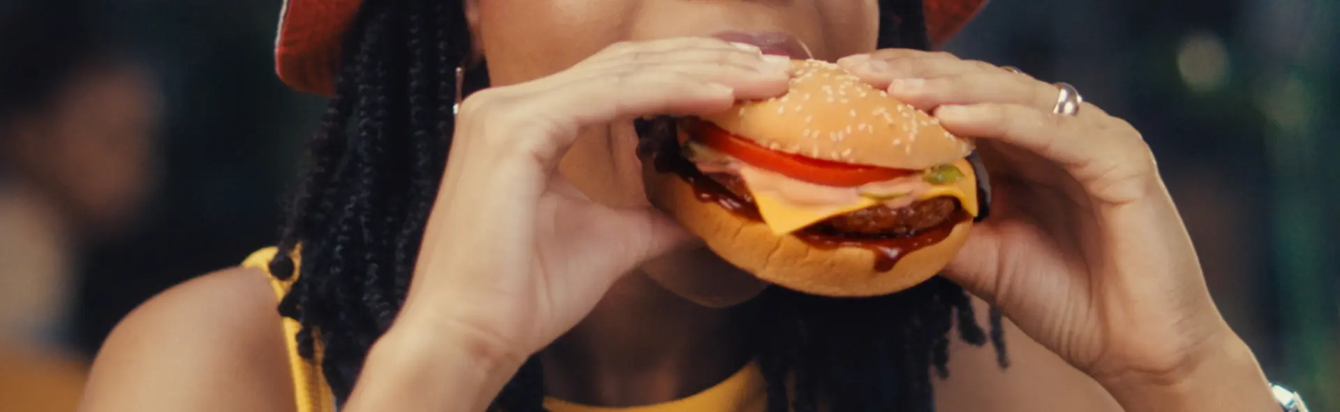 Person taking a bite out of a beef cheese burger