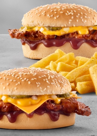 Two ribster burgers with melted cheese sauce, pickles, sesame seed buns, barbecue sauce, with chips